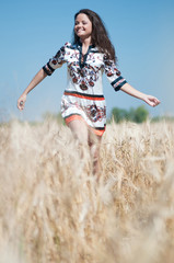 Beautiful woman walk in wheat field on sunny summer day.