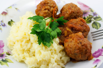 A dish of rice and meatballs in tomato sauce