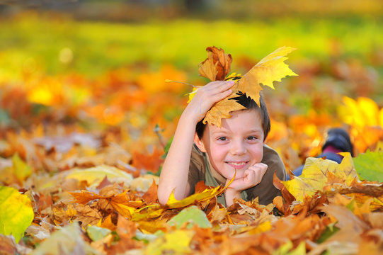 Boy In Autumn Forest Playing With Leaves