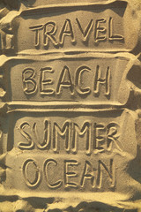 handwriten words on sand - travel, beach, summer and ocean