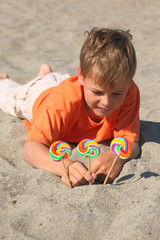caucasian boy in orange shirt lying on beach