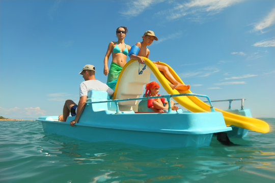 happy family with boy and girl on pedal boat with yellow slide