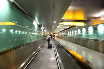 people go into long, green corridor for boarding at airplane