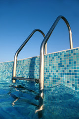shiny chrome ladder into pool, blue sky, blue water, blue bottom