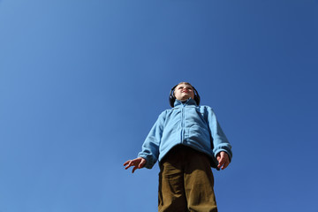 little boy in jacket and big black headphones listens to music