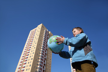 little boy in blue jacket holding balloon in form of globe