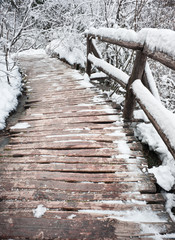 Wooden bridge in snow close-up. Winter forest of Plitvice