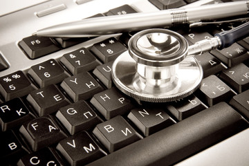 shiny stethoscope and silver pen on keyboard