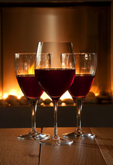 Red wine glasses in front of a fire