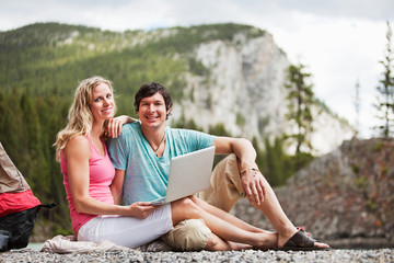 Naklejka na ściany i meble Relaxed couple with laptop while camping