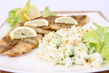 Fried fish with celery side salad decorated with lemon