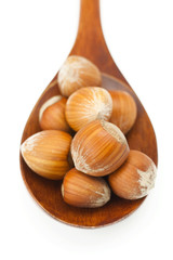 hazelnuts on a wooden spoon isolated on white