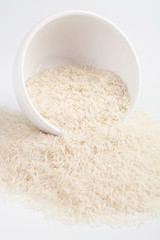 Uncooked basmati rice in a ceramic bowl on white background