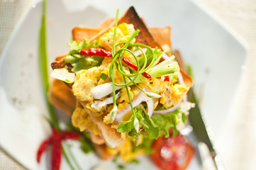 Skyscraper of toast with scrambled eggs tomatos and salat