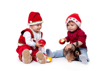 Two kids in Santa hats with a rabbit