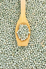 Wooden spoon and dried green split peas.