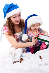 Mother and daughter in Santa's hat sitting in artificial snow