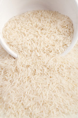 Uncooked basmati rice in a ceramic bowl on white background