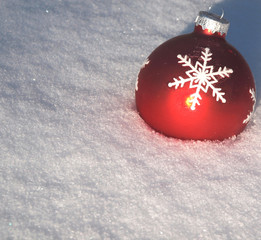 Rote Weihnachtskugel im Schnee