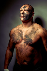Fototapeta na wymiar Emotional portrait of fighter. War paint on his face and body