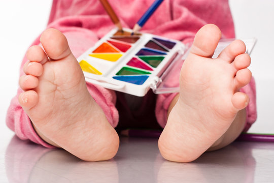 Baby's feet with paint and pencils