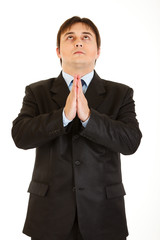 Young businessman praying for success isolated on white.
