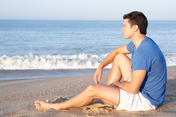 Fototapeta na wymiar Man sitting on beach relaxing