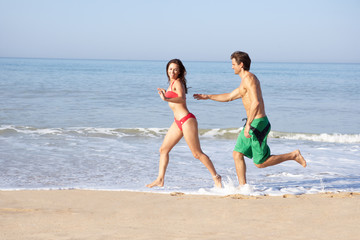 Fototapeta na wymiar Young couple running on beach