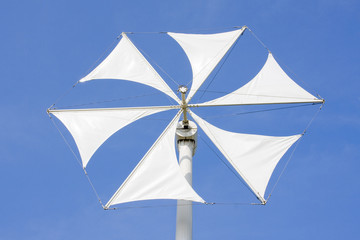 White wind turbine generating electricity on blue sky
