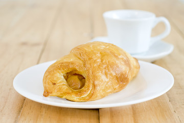 A cup of black coffee with Plate of sausage rolls