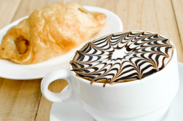 A cup of coffee with plate of sausage roll