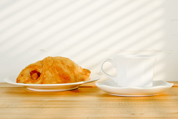 A cup of black coffee with Plate of sausage rolls