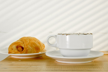 A cup of black coffee with Plate of sausage rolls
