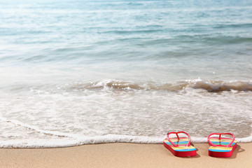 Fototapeta na wymiar Flipflops on a sandy ocean beach
