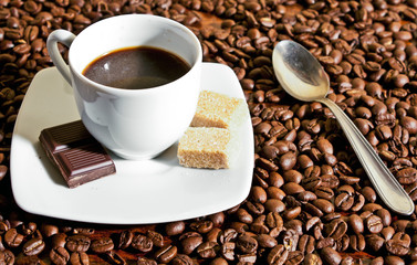 Cup of coffee with chocolate and coffee grain background