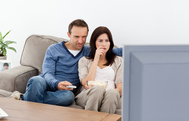 Fototapeta na wymiar Uprzejmy para oglądając horror w telewizji