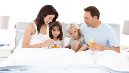 Obraz na płótnie Canvas Lovely family having breakfast on the bed