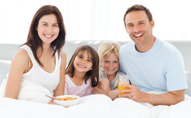 Cheerful family having breakfast together on the bed