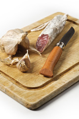 Rustic still life with cutting board, smoked sausage, garlic and