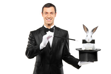 A magician in a black suit holding a top hat with a rabbit in it
