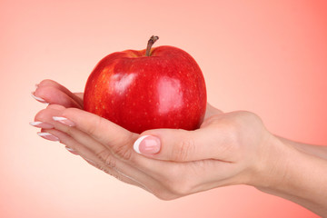 Woman hands holding an apple on red background