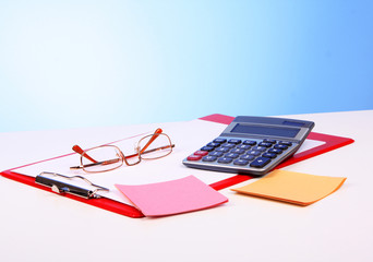 Glasses, calculator and paper on table