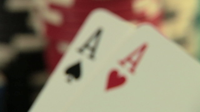 Pocket aces in a deck of playing cards with poker chips