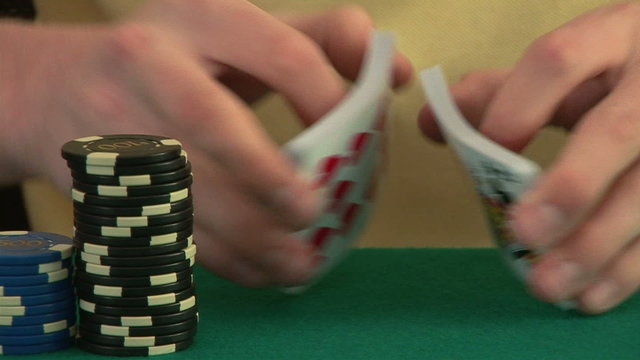 Hands on a poker table shuffling a deck of cards and dealing