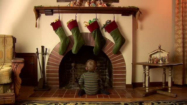 Toddler in pajamas looking for Santa in the fireplace