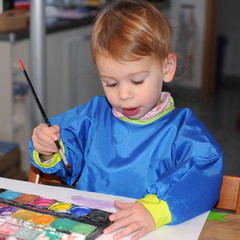 Kleines Mädchen beim Malen mit Pinsel und Farben