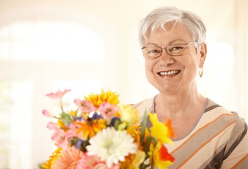 Portrait of happy senior woman with flowers