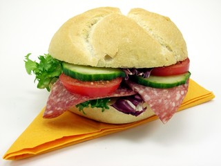 A bread roll filled with salami, tomato, cucumber & salad