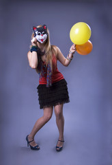 Girl with balloons in mask of cat.