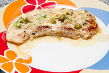 fried steak with caper sauce on the plate